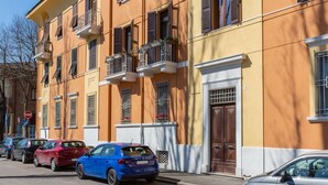 A row of parked cars along a street with a building featuring balconies and a door marked with the number 16. - GuestHost - Ferrara Station Essential Apartment w/parking (Ferrara)