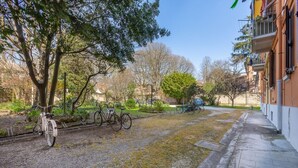 A paved pathway, bicycles, a tree, and a building with balconies. - GuestHost - Ferrara Station Essential Apartment w/parking (Ferrara)