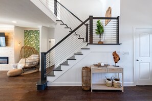 A modern staircase with a black railing, a white wall, and a wooden floor.