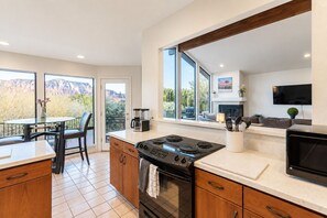 Een moderne keuken met een groot fornuis, houten keukenkastjes en een eethoek met een tafel en stoelen.