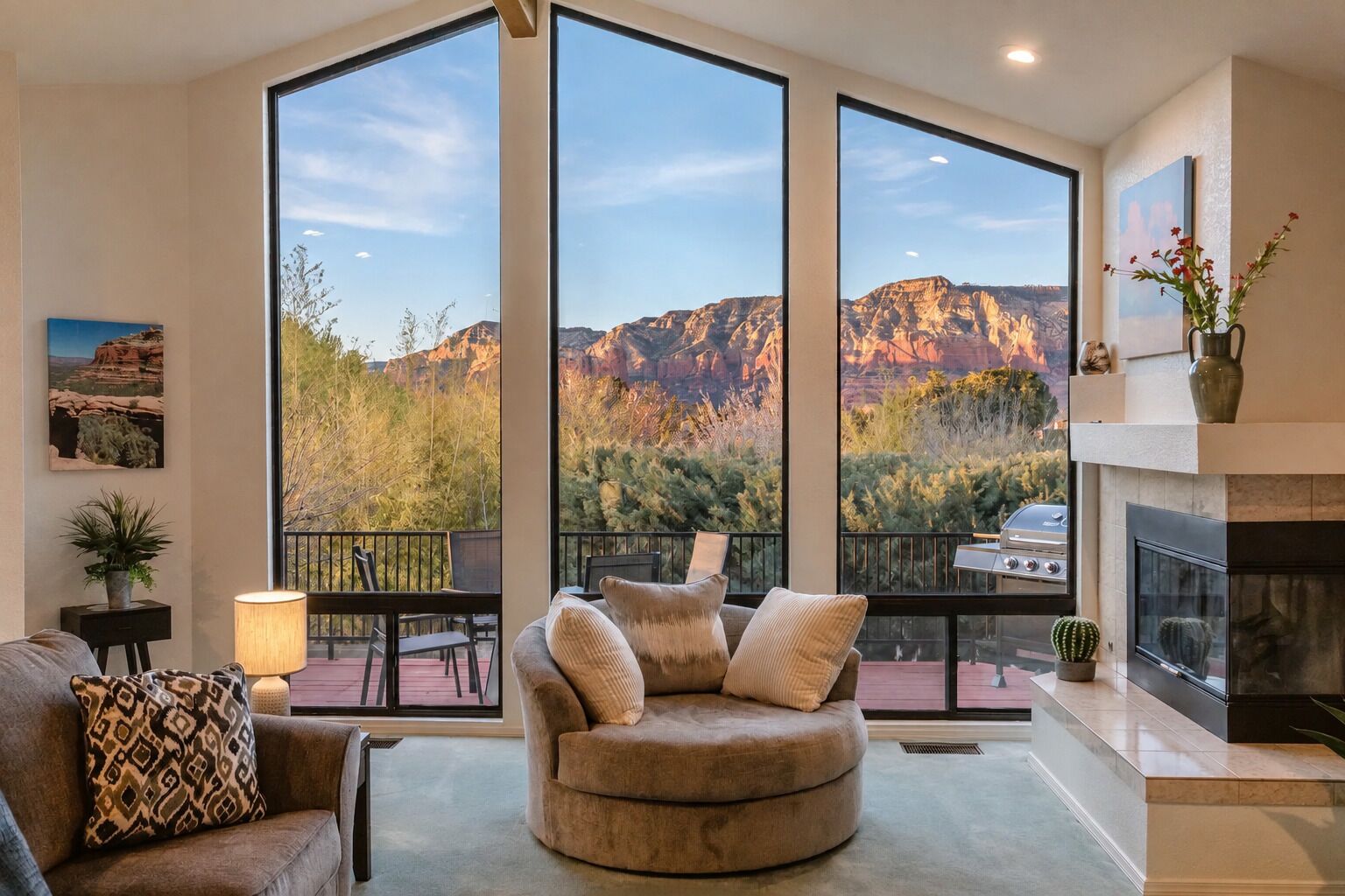A spacious living room with a large window overlooking a mountainous landscape, a fireplace, and a comfortable seating area.