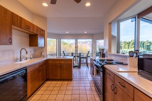 Una cocina moderna con armarios de madera, lavavajillas, estufa y ventanas amplias que ofrecen vistas a montañas.