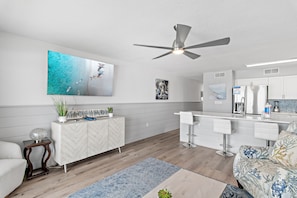 Eine moderne Küche mit weißen Schränken, einer Bar und einem Deckenventilator.