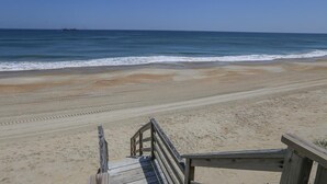A beach with a wooden walkway leading to the water.