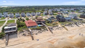 A coastal residential area with houses, a beach, and a pier.