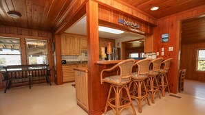 A wooden interior with a bar area featuring wicker chairs and a bench.