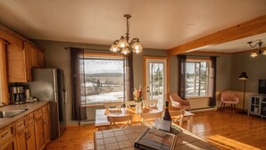 A spacious kitchen with wooden cabinets, a refrigerator, and a dining area with a table and chairs. - Les Chalets Tourisma - La Campagnarde (Saint-Leonard-de-Portneuf)