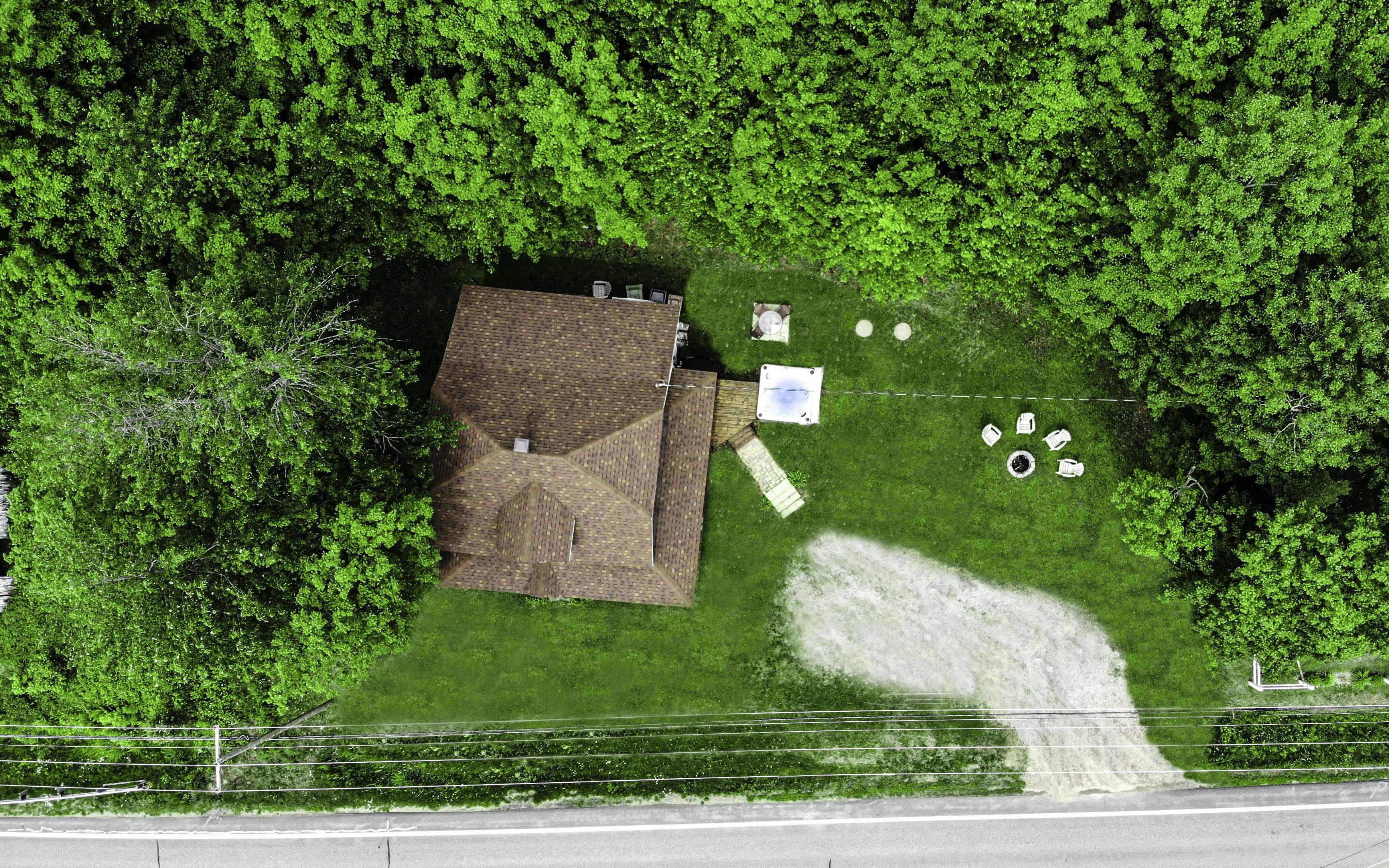An aerial view of a property with a large building, a fenced yard, and several outdoor seating areas.