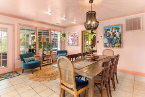 A dining area with a wooden table, chairs, and a hanging light fixture. - Creekside Paradise • Sunsets, Pool, Spa, Dock, Kayaks (Tybee Island)