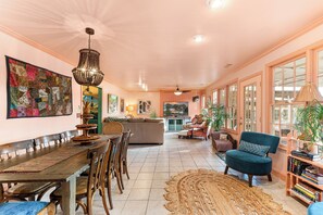 A spacious living area with a dining table, chairs, a sofa, and a television. - Creekside Paradise • Sunsets, Pool, Spa, Dock, Kayaks (Tybee Island)