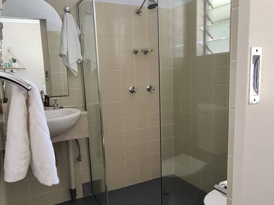 Een moderne badkamer met een douchecabine van glas, een witte wastafel en een toilet.