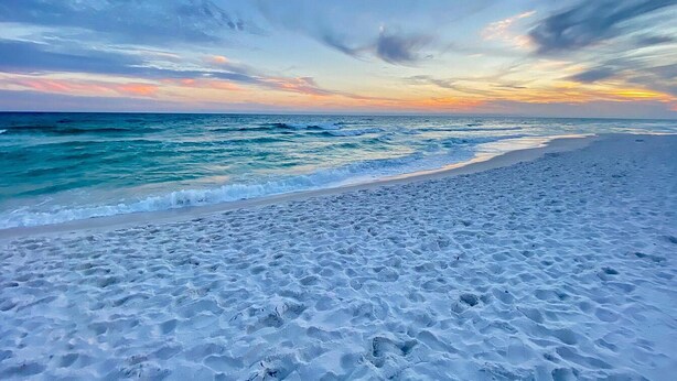 Ein Strand mit weitem, sandigen Ufer und sanften Wellen.