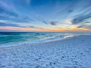 A beach with a wide sandy shore and gentle waves. - Beach and Resort home! New 6 seater golf cart, beach access and pools! (Miramar Beach)