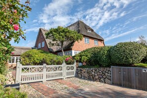A house with a thatched roof, a stone wall, and a wooden gate.