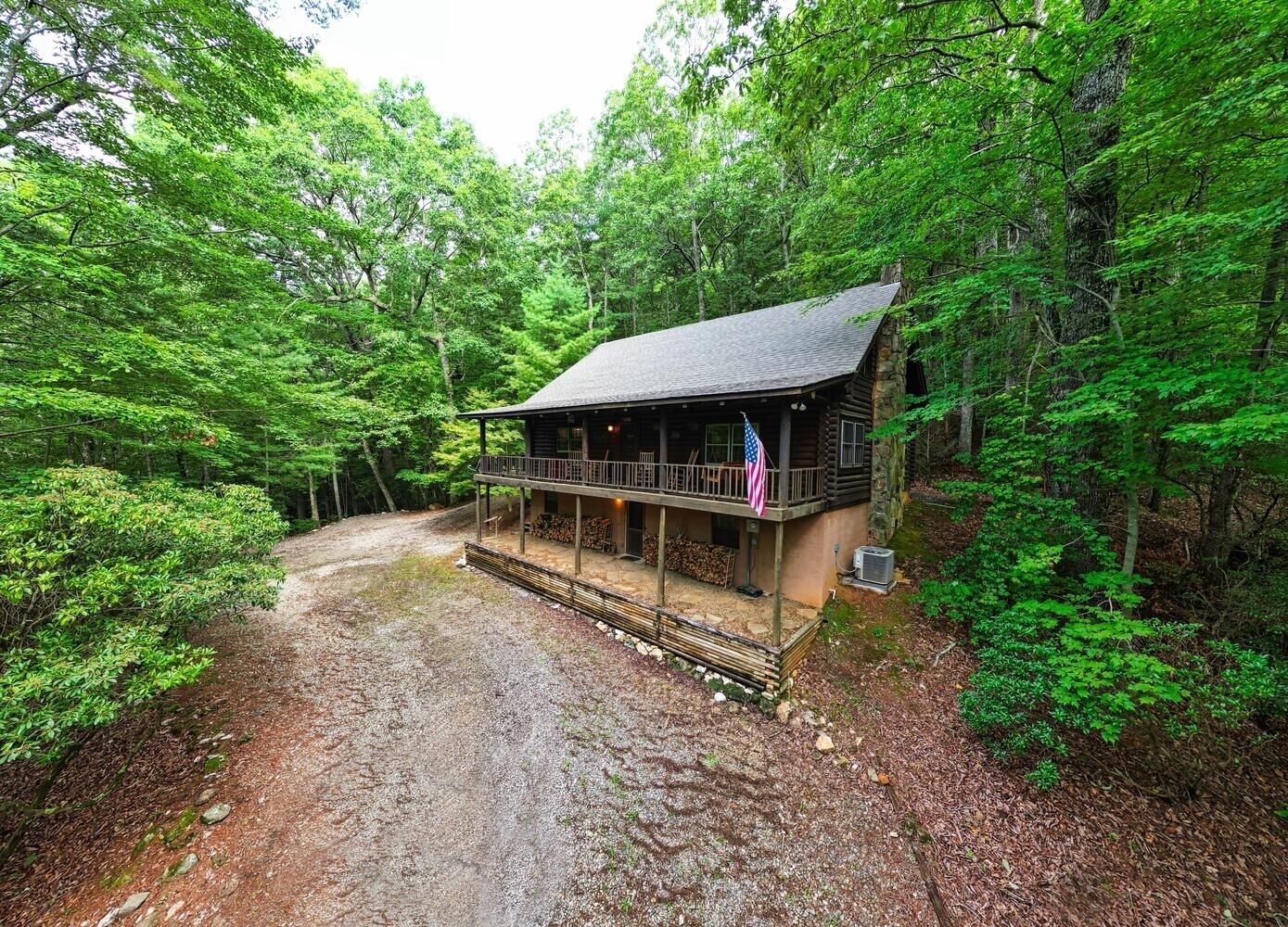 A cabin with a porch, surrounded by dense forest.
