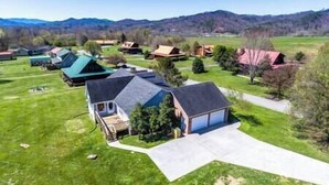 A residential area with multiple houses, each with a distinct roof style and surrounded by green lawns.