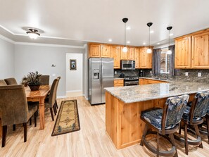 A modern kitchen with wooden cabinets, stainless steel appliances, and a granite countertop.