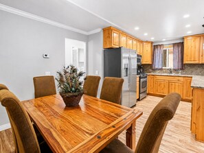 Een moderne keuken met houten kasten, een roestvrijstalen koelkast en een eethoek met een houten tafel en stoelen.