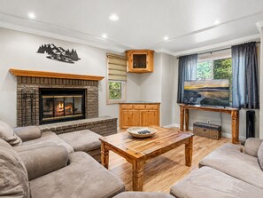 Una sala de estar con chimenea, televisor y vistas al exterior.
