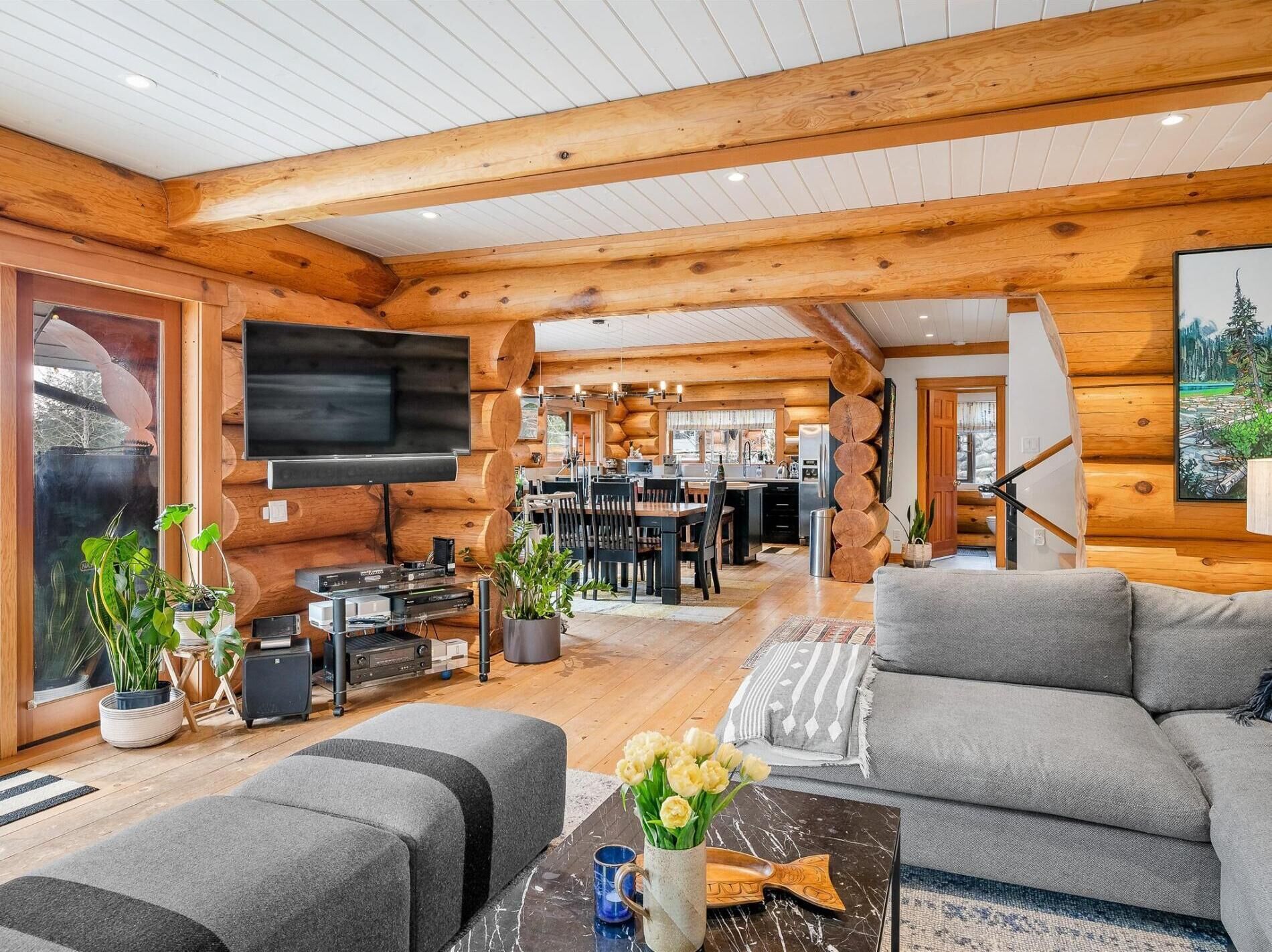 A log cabin interior with a living room, dining area, and kitchen.