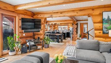 A log cabin interior with a living room, dining area, and kitchen.