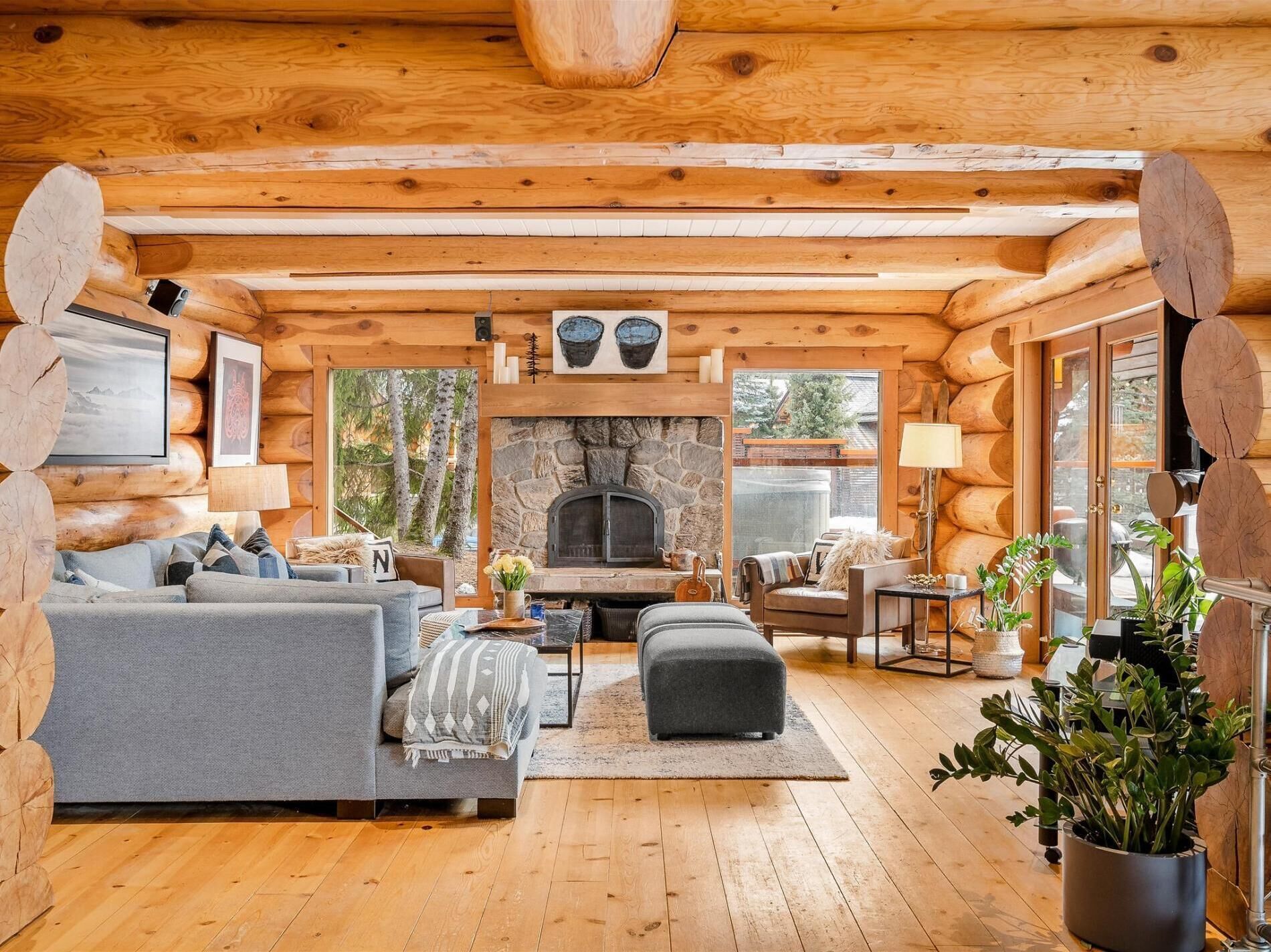 L’intérieur chaleureux d’un chalet en bois, avec une cheminée en pierre, des murs en bois et un coin salon confortable.