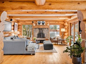 L’intérieur chaleureux d’un chalet en bois, avec une cheminée en pierre, des murs en bois et un coin salon confortable.