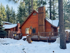 A log cabin with a wooden deck and a chimney.