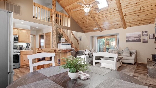 A spacious kitchen with wooden cabinets, a dining area with a large table and chairs, and a staircase leading to an upper level.