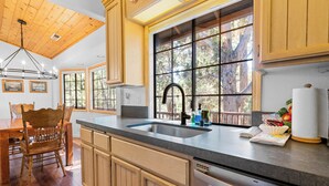 A kitchen with wooden cabinets, a large window, and a built-in dishwasher.