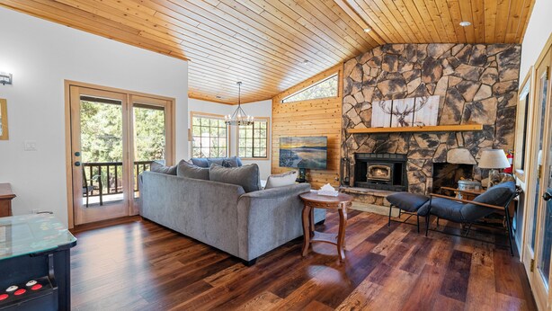 A spacious living room with a stone fireplace, wooden ceiling, and a large sofa.