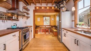 Una cucina con pavimento in legno, pensili bianchi, un fornello e un frigorifero.