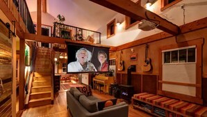 Un accogliente soggiorno con una scala in legno, una televisione a schermo piatto, un divano, un caminetto e una libreria.