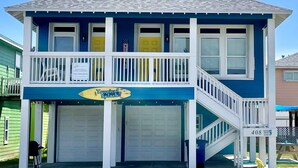 A two-story building with a blue exterior and white trim, featuring a balcony and a garage. - 2 Homes- Perfect location for large families or groups. Pool, Walk to BEACH (Port Aransas)