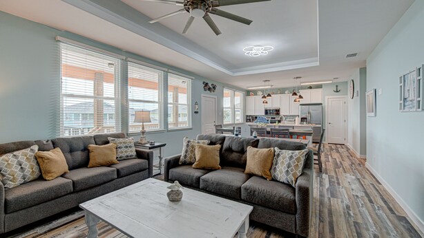 A spacious living room with a grey sofa set, a white coffee table, and a ceiling fan. - 2 Homes- Perfect location for large families or groups. Pool, Walk to BEACH (Port Aransas)