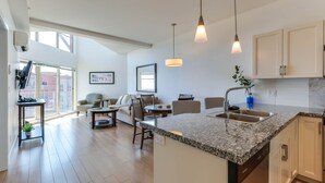 A modern kitchen with granite countertops, a built-in dishwasher, and pendant lighting. - Stunning Lake View Condo (West Kelowna)