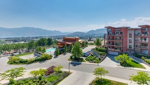 A hotel with a pool, multiple floors, and a view of mountains. - Stunning Lake View Condo (West Kelowna)