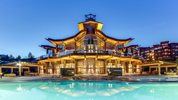 A large, multi-story hotel with a pool in the foreground. - Stunning Lake View Condo (West Kelowna)
