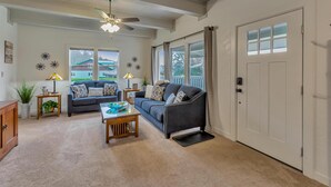 A living room with a ceiling fan, a sofa, a coffee table, and a door with frosted glass panels. - Redondo Beach Bungalow (Des Moines)