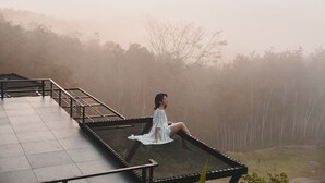 Une personne assise sur un banc en métal, avec vue sur une zone boisée.