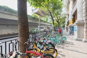 A row of bicycles parked along a sidewalk next to a building with classical architecture.