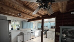 A spacious kitchen with white cabinets, a central island, and a wooden ceiling.