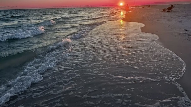 A beach at sunset with waves gently lapping the shore.