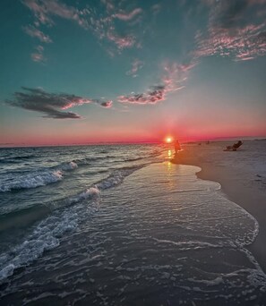 A beach at sunset with waves gently lapping the shore.