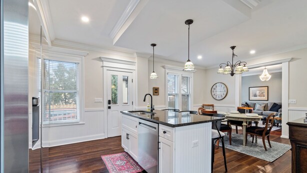 Una cocina amplia con una isla central, iluminación colgante y un comedor con candelabro.