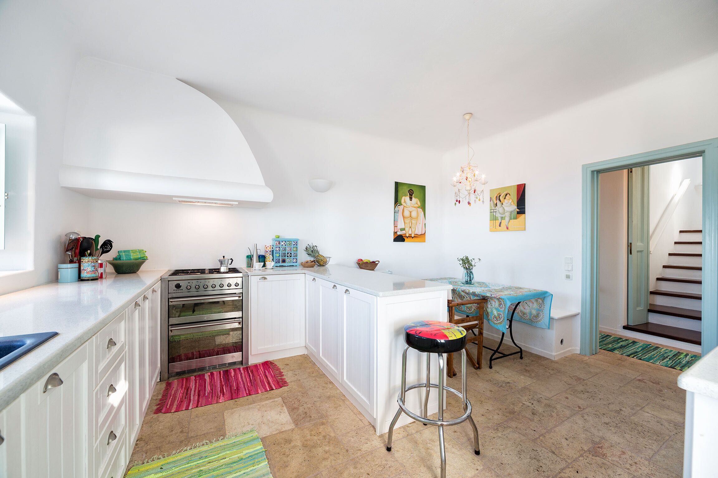 A kitchen with white cabinets, a stove, and a dining area with a table and chairs.