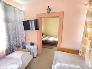 A bedroom with two beds, a TV mounted on the wall, and a small table with a power outlet. - Beachfront Apartment - Sleeps 4 & Free Parking (Arginonta)