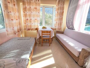 A room with a bed, a sofa, a dining table with chairs, and a window with curtains. - Beachfront Apartment - Sleeps 4 & Free Parking (Arginonta)