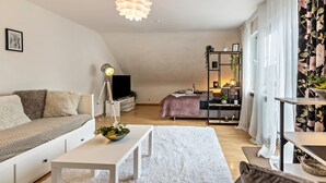 Una sala de estar moderna con un sofá, una mesa de centro, un televisor y un comedor con una mesa y sillas.