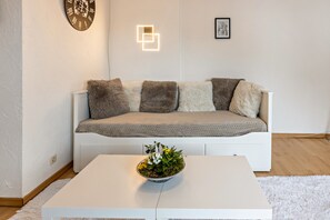 Un salon moderne avec un canapé blanc, une table basse blanche et un bol décoratif posé sur la table.